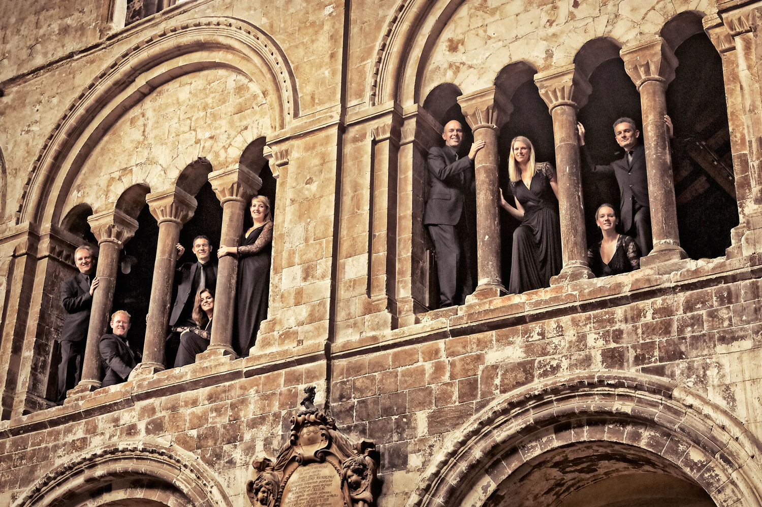 mehrere Personen schauen, teils sitzend, teils stehend durch Kirchenfenster nach unten